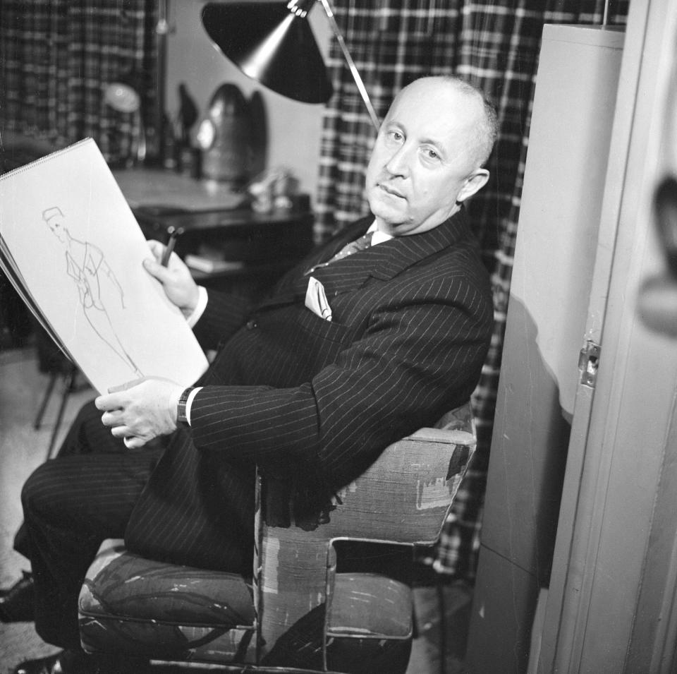 French fashion designer Christian Dior  sits in a chair with a sketchpad, on which is a fashion design, for a broadcast of the CBS celebrity interview program 'Person to Person,' November 7, 1955.