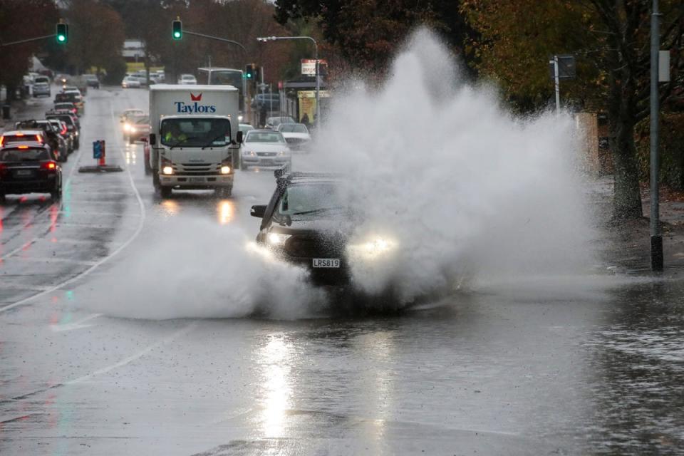 Cars plough through water in the flooded streets of central Auckland, New Zealand (AP)