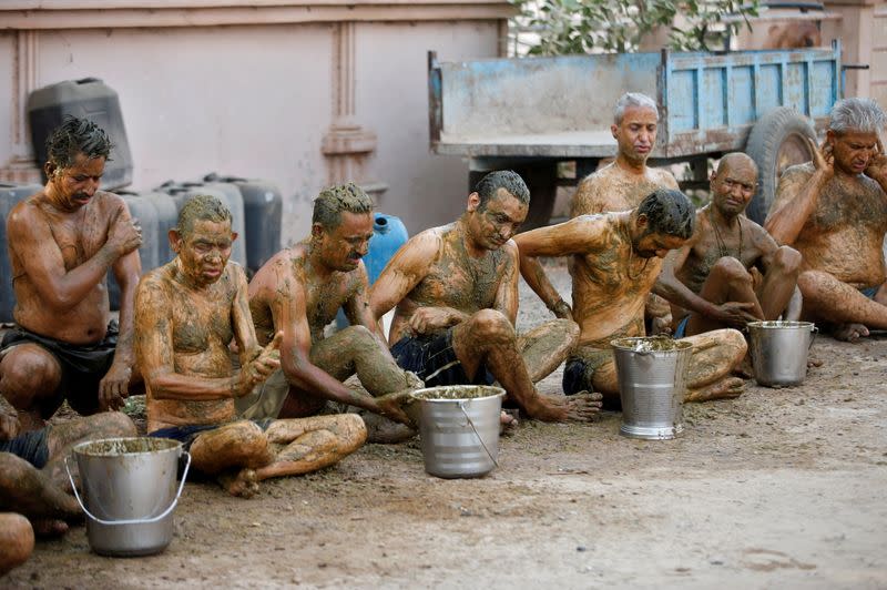 People apply cow dung on their bodies during "cow dung therapy" on outskirts of Ahmedabad