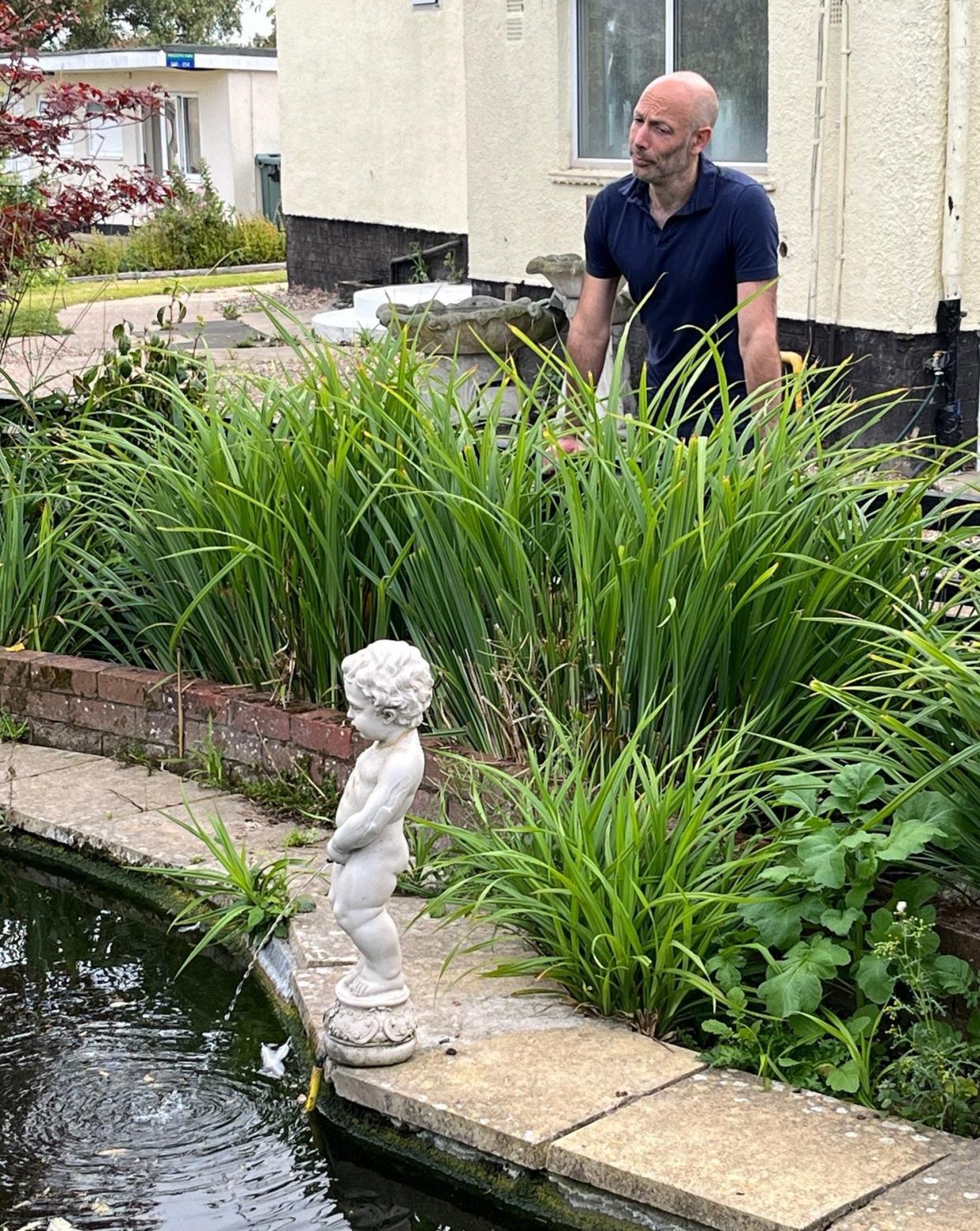 A mini Manneken Pis urinating into a pond