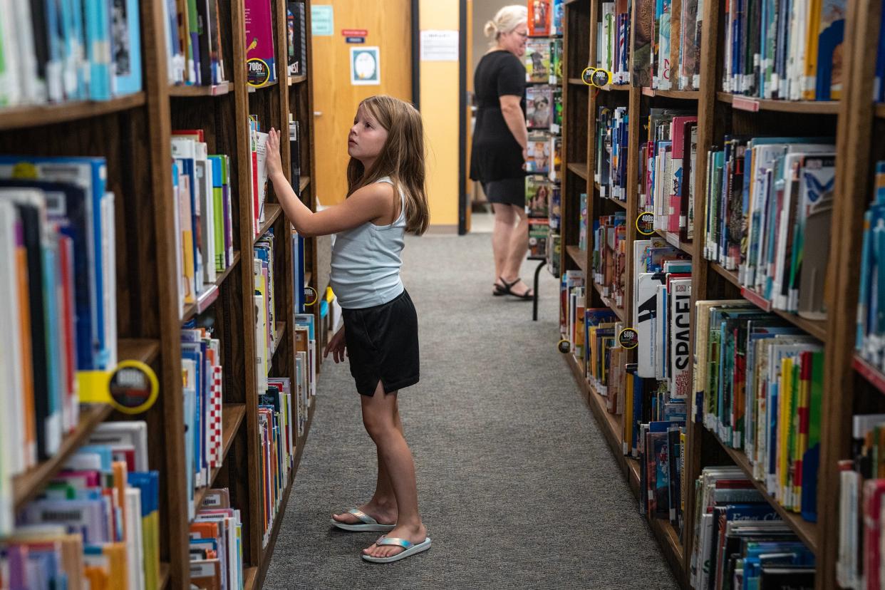 Ella Stout, of Alta, searches the shelves of the Alta Community Library to find something to read, on Tuesday, August 1, 2023, in Alta. The library is shared by the community and the school district.