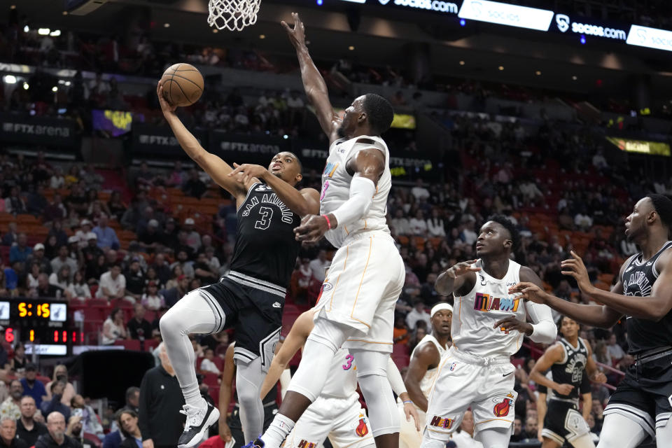 San Antonio Spurs forward Keldon Johnson (3) goes to the basket as Miami Heat center Bam Adebayo, center, defends during the first half of an NBA basketball game, Saturday, Dec. 10, 2022, in Miami. (AP Photo/Lynne Sladky)