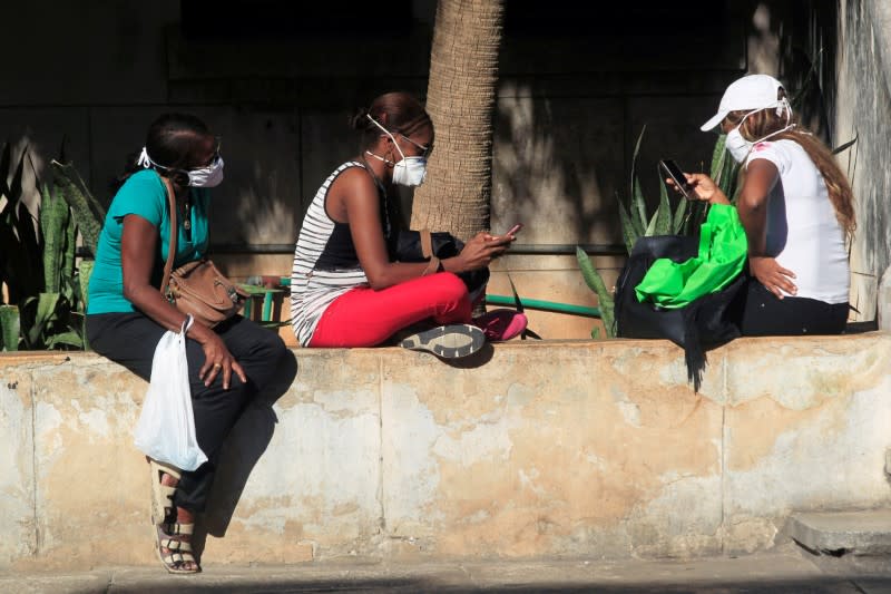 People use their mobile phones wearing protective masks amid concerns about the spread of the coronavirus disease (COVID-19) outbreak in Havana