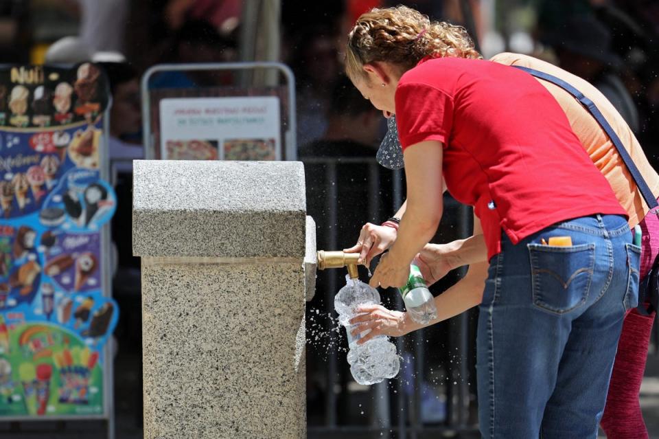 People fill bottles by a fountain at the Retiro Park in Madrid on July 11 (AFP via Getty Images)