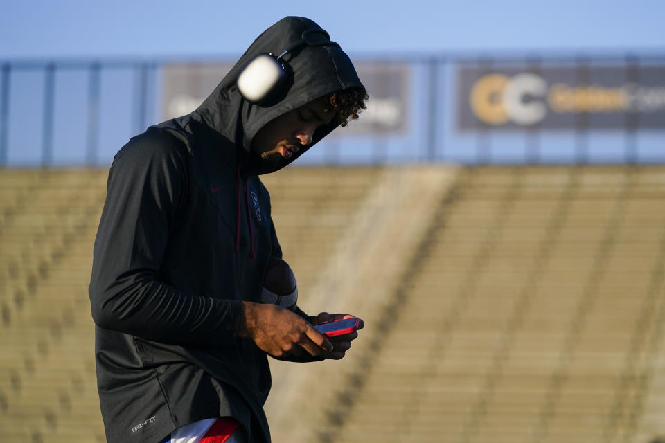 Los Alamitos High School quarterback Malachi Nelson looks at his phone while warming up before a high school football game against Newport Harbor High School on Friday, Sept. 30, 2022, in Newport Beach, Calif. (AP Photo/Ashley Landis)