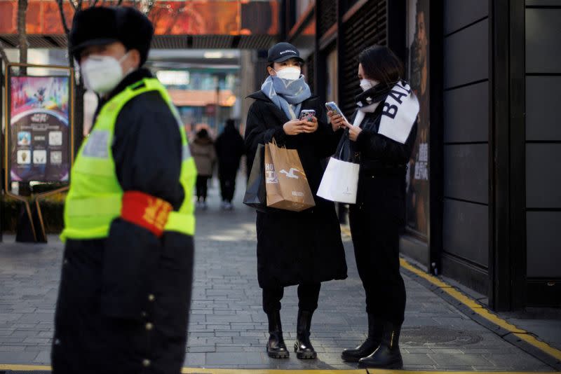 FILE PHOTO: Women with shopping bags stand in a street as China returns to work despite continuing coronavirus disease (COVID-19) outbreaks in Beijing