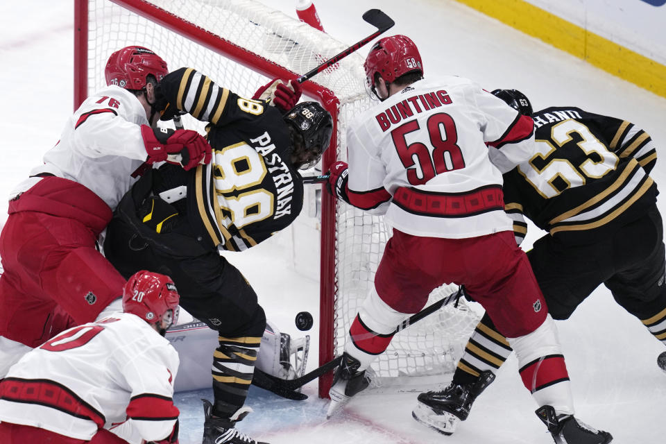 Boston Bruins right wing David Pastrnak (88) and left wing Brad Marchand (63) work against Carolina Hurricanes left wing Michael Bunting (58) for the puck during the first period of an NHL hockey game, Wednesday, Jan. 24, 2024, in Boston. (AP Photo/Charles Krupa)