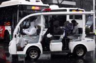 Worker in protective suit drives a vehicle amid snow to transport novel coronavirus patients outside a hospital in Wuhan