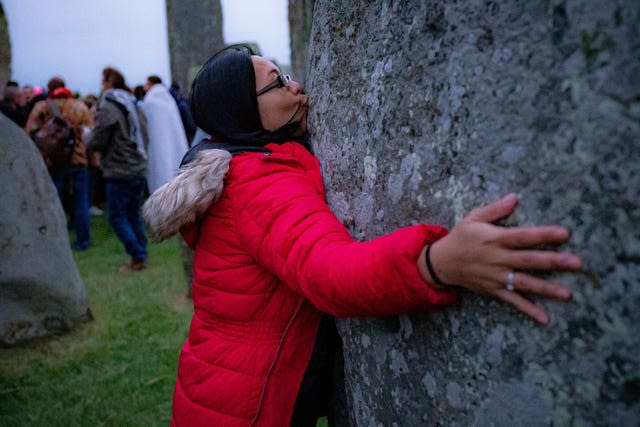 A woman kisses a stone during Summer Solstice