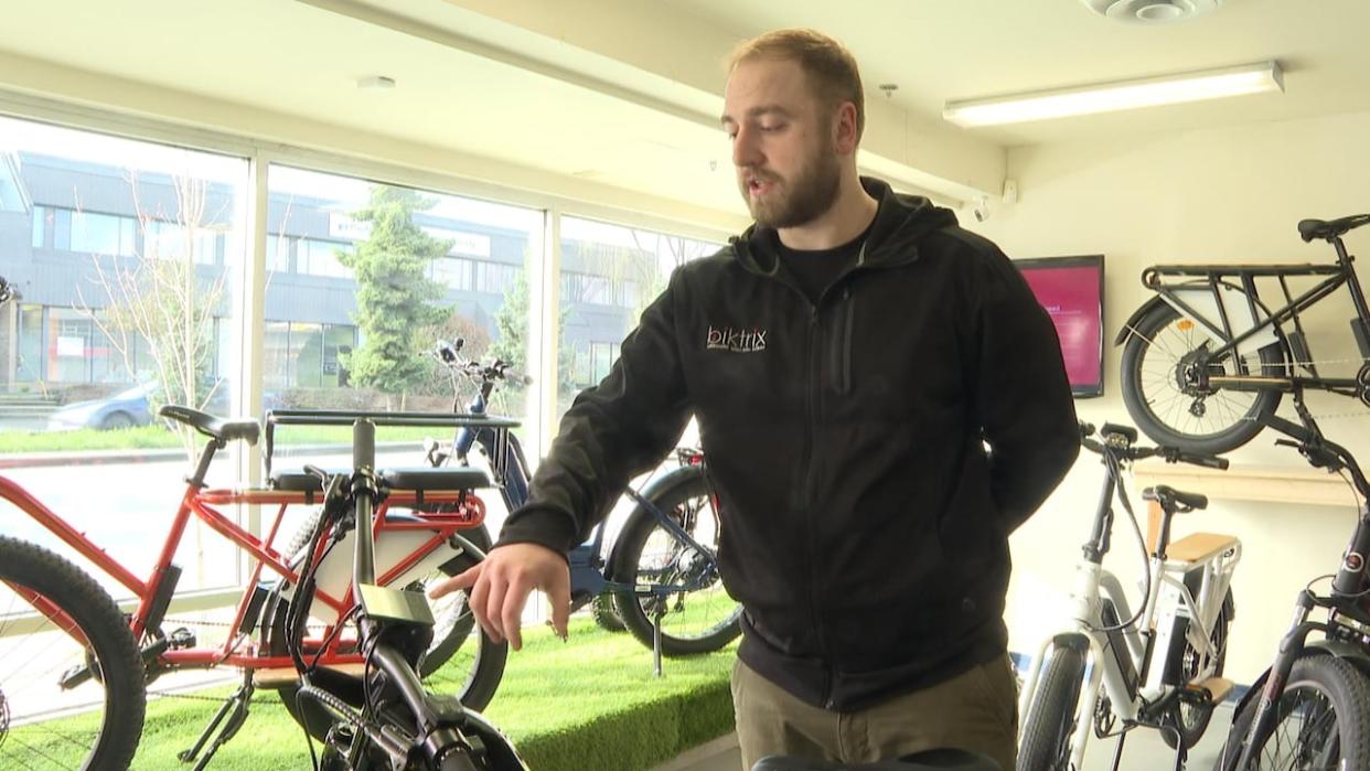 The manager of Biktrix's Vancouver showroom, Dillon Terry, points out some of the manufacturer's bikes on Sunday. More than 140 e-bikes were taken as a cargo container was stolen in Metro Vancouver earlier this week.  (Sohrab Sandhu/CBC - image credit)