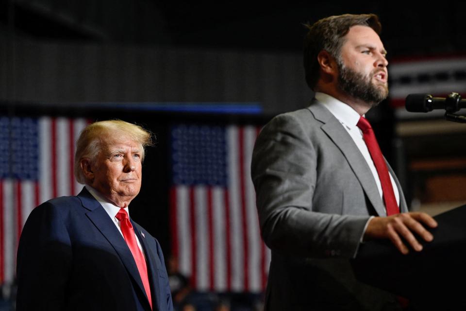 Former President Donald Trump listens as JD Vance speaks during a rally