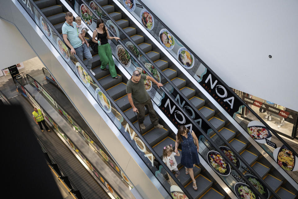 Valentyn Lytvynchuk, a former battalion commander of the 5th brigade, walks downstairs with his family at the trade center in Lviv, Ukraine, Thursday, July 20, 2023. Ukraine is facing the prospect of a future with upwards of 20,000 amputees, many of them soldiers who are also suffering psychological trauma from their time at the front. (AP Photo/Evgeniy Maloletka)