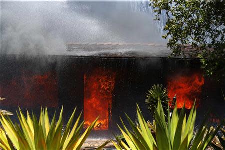 A burning home is doused with water as firefighters battle with wildfires in Carlsbad, California May 14, 2014. REUTERS/Mike Blake