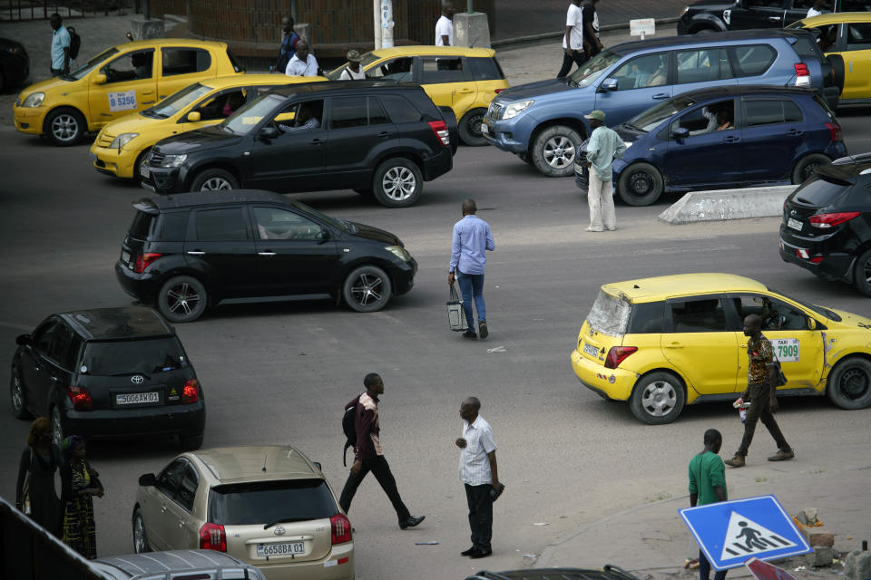 Pedestrians slalom between traffic to cross the road in Kinshasa, Congo, Tuesday Jan. 8, 2019. As Congo anxiously awaits the outcome of the presidential election, many in the capital say they are convinced that the opposition won and that the delay in announcing results is allowing manipulation in favor of the ruling party. (AP Photo/Jerome Delay)
