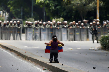 A demonstrator knees in front of riot police during a rally against Venezuela's President Nicolas Maduro in Caracas, Venezuela April 20, 2017. REUTERS/Carlos Garcia Rawlins