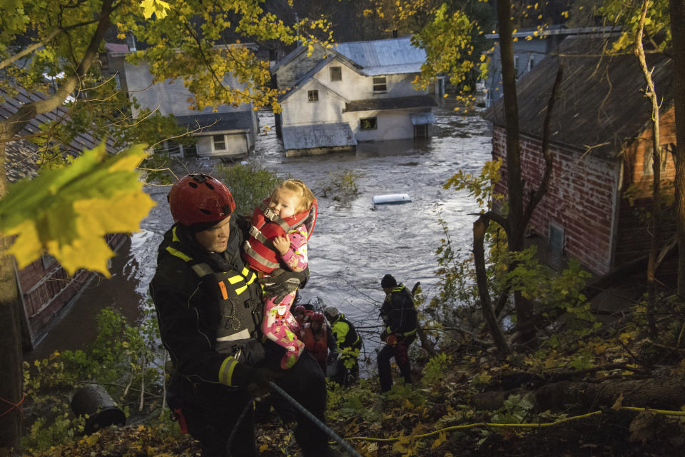 In this photo provided by the New York State Governor's Office, a first responder carries a young girl to safety after she was rescued from a house being flooded by rising waters of the East Canada Creek, Friday, Nov. 1, 2019 in Dolgeville, N.Y. Several hundred people were being evacuated in scattered areas around the state because of high waters. (Darren McGee/New York State Governor's Office via AP)