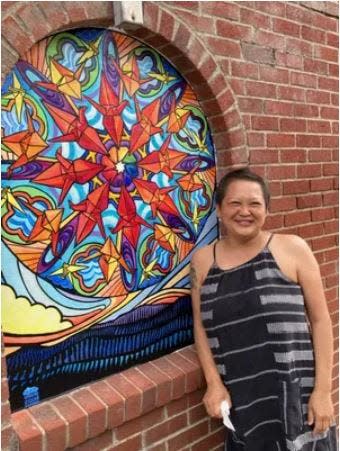 Lara Nguyen poses in front of "Find Your Center," one of four murals she designed for the North Carolina Arts Council's SmART Communities program.