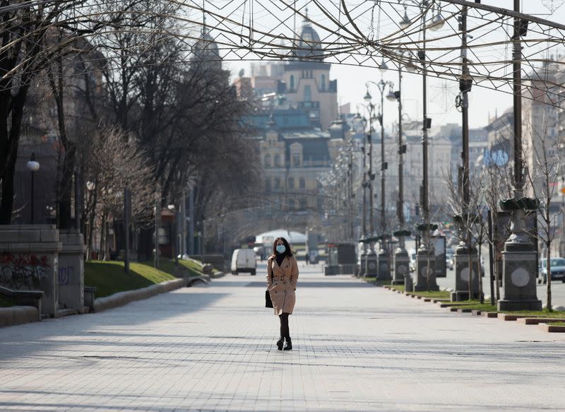 Foto del jueves de una mujer con una máscara caminando por el centro de Kiev