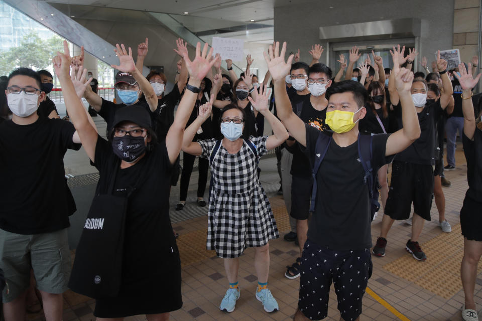 Protesters gesture with five fingers, signifying the "Five demands - not one less" outside a court during a protest in Hong Kong, Thursday, Aug. 27, 2020. Hong Kong police arrested 16 people, including two opposition lawmakers, on Wednesday on charges related to anti-government protests last year. (AP Photo/Kin Cheung)