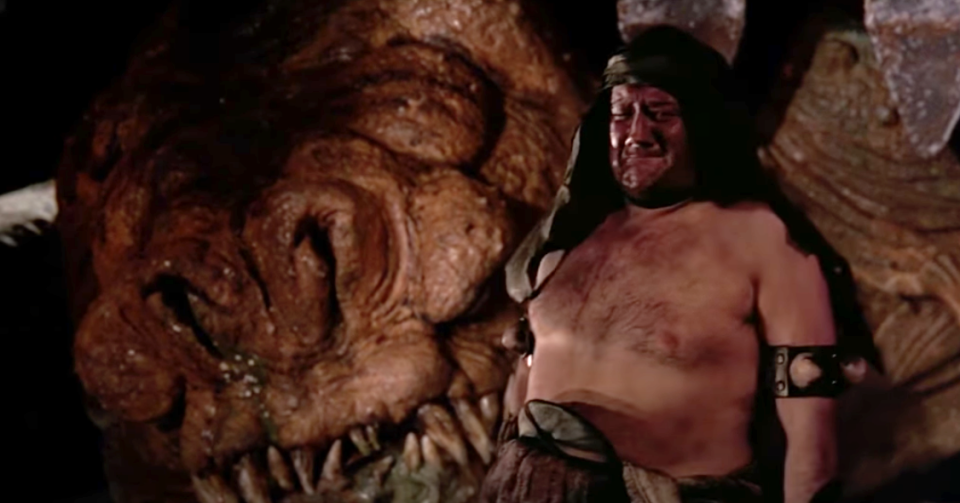 A Rancor keeper with no shirt, and a headdress, crying because his Rancor is dead