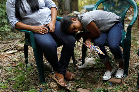 Marcela, 9, daughter of Douglas Almendarez, 37, a deportee from the U.S. who was separated from his son Eduardo Almendarez, 11, at the Rio Grande entry point under the Trump administration's hardline immigration policy, rests on her mother's leg, in La Union, in Olancho state Honduras July 14, 2018. Picture taken July 14, 2018. REUTERS/Edgard Garrido