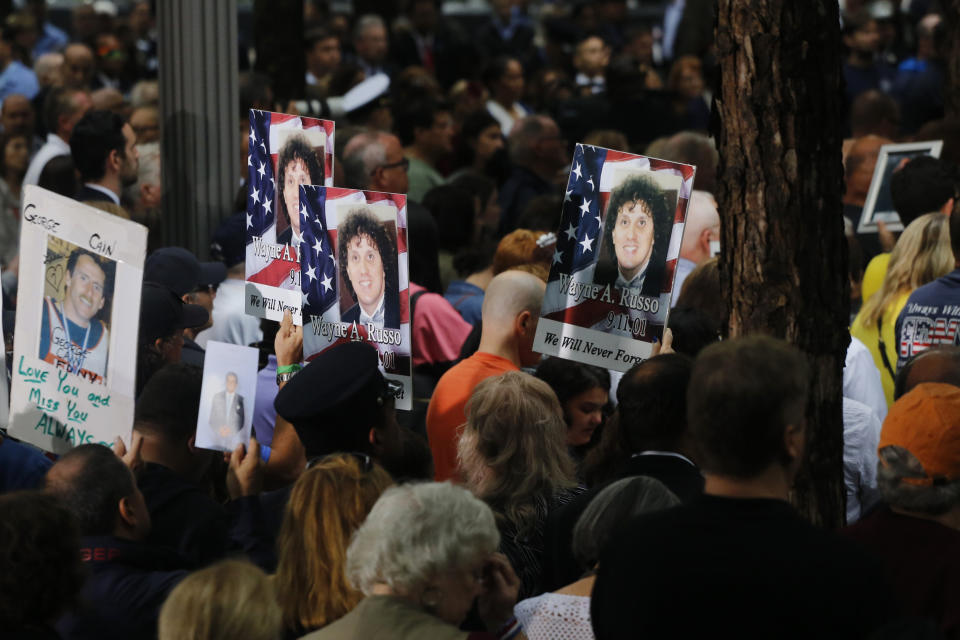 People hold up photo memorials during a ceremony marking the 17th anniversary of the terrorist attacks on the United States on Tuesday, Sept. 11, 2018, in New York. (AP Photo/Mark Lennihan)