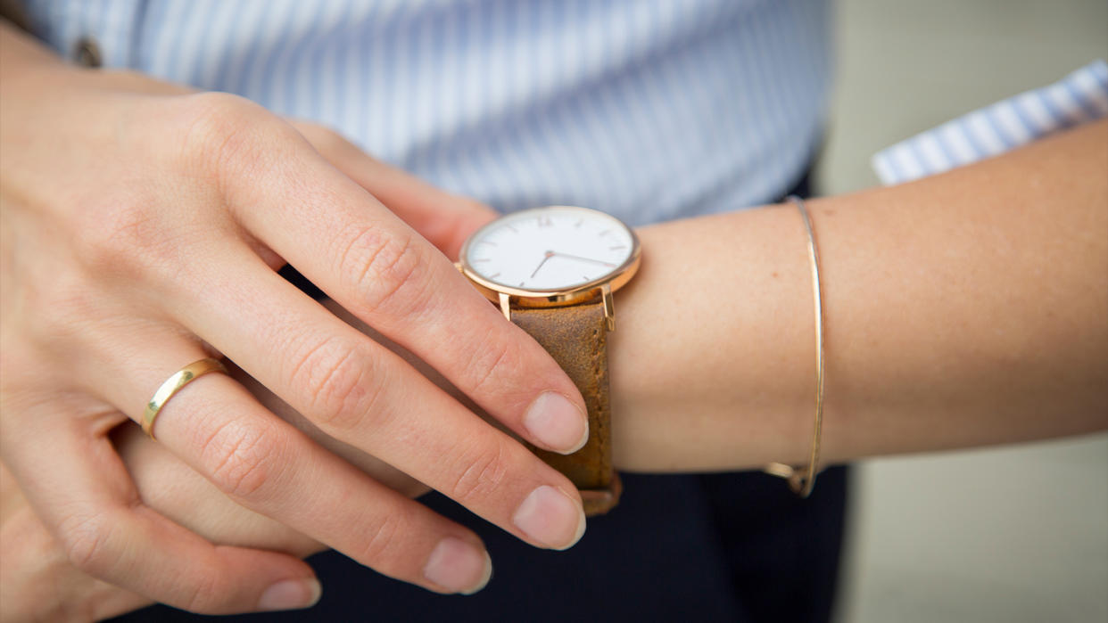  Close up on a woman's gold and white wristwatch as she checks it for the time. 