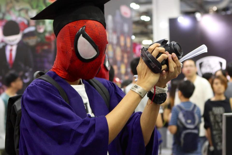 A Spiderman cosplayer taking a picture of an action figure. (Photo: Sharlene Sankaran/ Yahoo Newsroom)