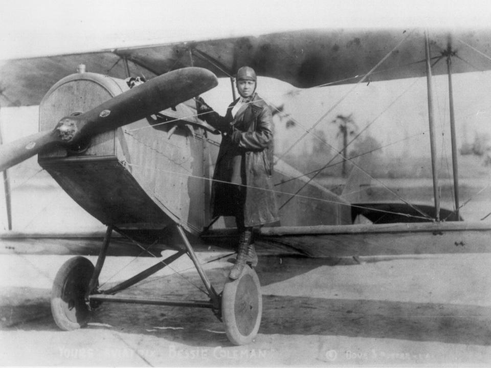 Black and white photo of Bessie Coleman in a small airplane.