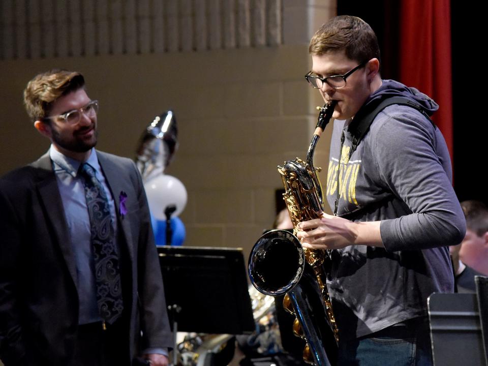 Monroe High School senior Christopher Gallaher, 17, starts to jam on his new baritone saxophone from Make-A-Wish Michigan as band director Joey Swinkey looks on.