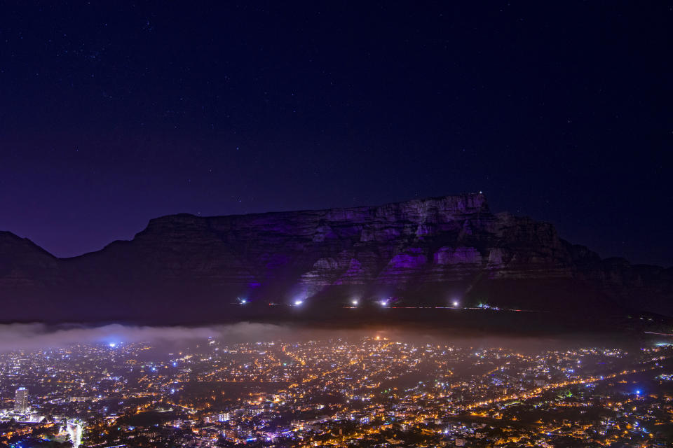 Table Mountain in Cape Town, South Africa is lit up in purple on Sunday, Dec. 26, 2021, in memory of Anglican Archbishop Desmond Tutu. South Africa's president says Tutu, South Africa's Nobel Peace Prize-winning activist for racial justice and LGBT rights and the retired Anglican Archbishop of Cape Town, has died at the age of 90. (AP Photo)