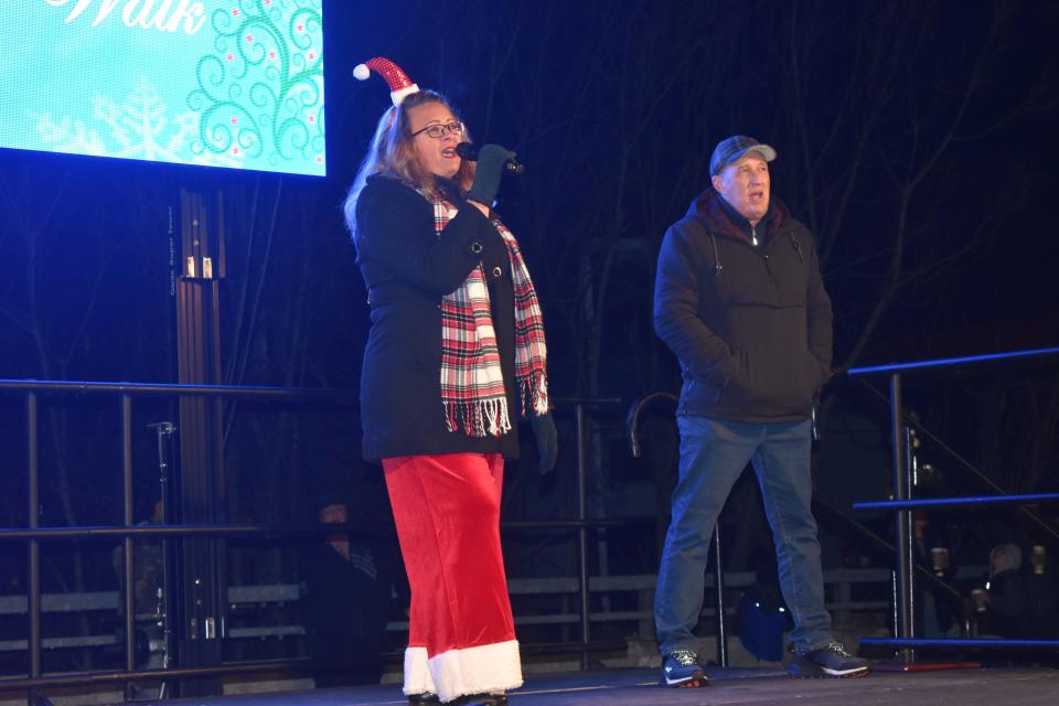 Adrian Mayor Angie Sword Heath, left, and city administrator Greg Elliott lead the audience Friday night at Comstock Park in the singing of "We Wish You a Merry Christmas" during the eighth annual Comstock Christmas Riverwalk lighting ceremony. The holiday event returned to an in-person setting for the first time since 2019.