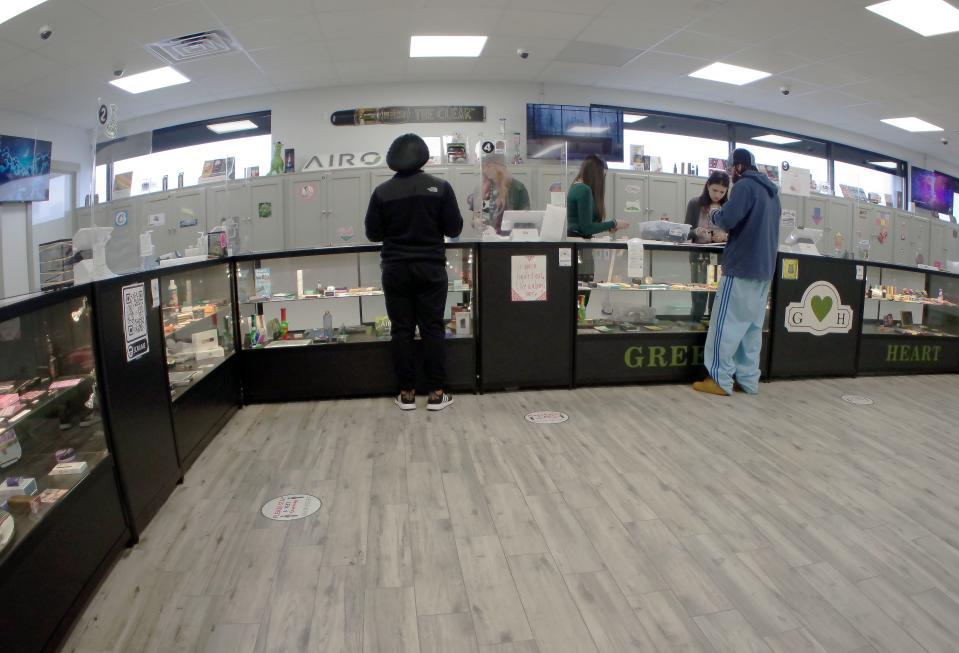 Workers assist customers at Green Heart Cannabis in Brockton on Wednesday, April 6, 2022.