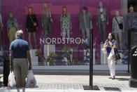 Shoppers walks past a Nordstrom window display at The Grove shopping center Wednesday, May 27, 2020, in Los Angeles. California moved to further relax its coronavirus restrictions and help the battered economy. Retail stores, including those at shopping malls, can open at 50% capacity. (AP Photo/Marcio Jose Sanchez)