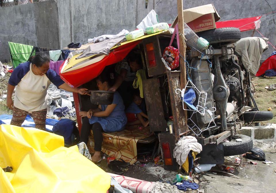 Homeless residents sit inside a damaged vehicle used as a makeshift shelter after super typhoon Haiyan hit Tacloban city, central Philippines November 11, 2013.