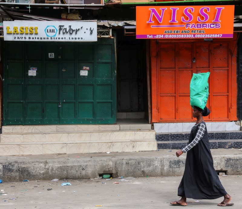 A woman walks beside closed shops in a nearly deserted wholesale market during lockdown by the authorities to limit the spread of coronavirus disease (COVID-19), in Lagos