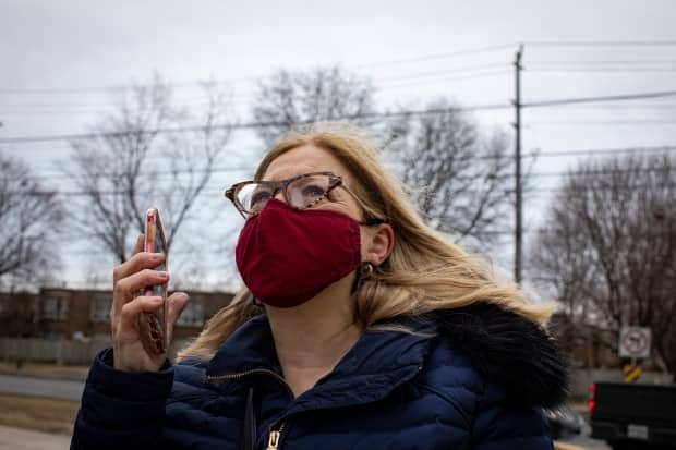 Susan Asa-Katz speaks to her mother on the phone outside Amica Thornhill, a retirement home in Thornhill, Ont., on March 18, 2021. At the time, residents were restricted to their rooms after two unvaccinated staff members tested positive for COVID-19. (Evan Mitsui/CBC - image credit)