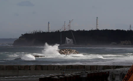 Wave is seen in front of cranes and chimneys of Tokyo Electric Power Co's (TEPCO) tsunami-crippled Fukushima Daiichi nuclear power plant at an area devastated by the March 11, 2011 earthquake and tsunami in Namie town, Fukushima prefecture, Japan May 19, 2018. Picture taken May 19, 2018. REUTERS/Toru Hanai