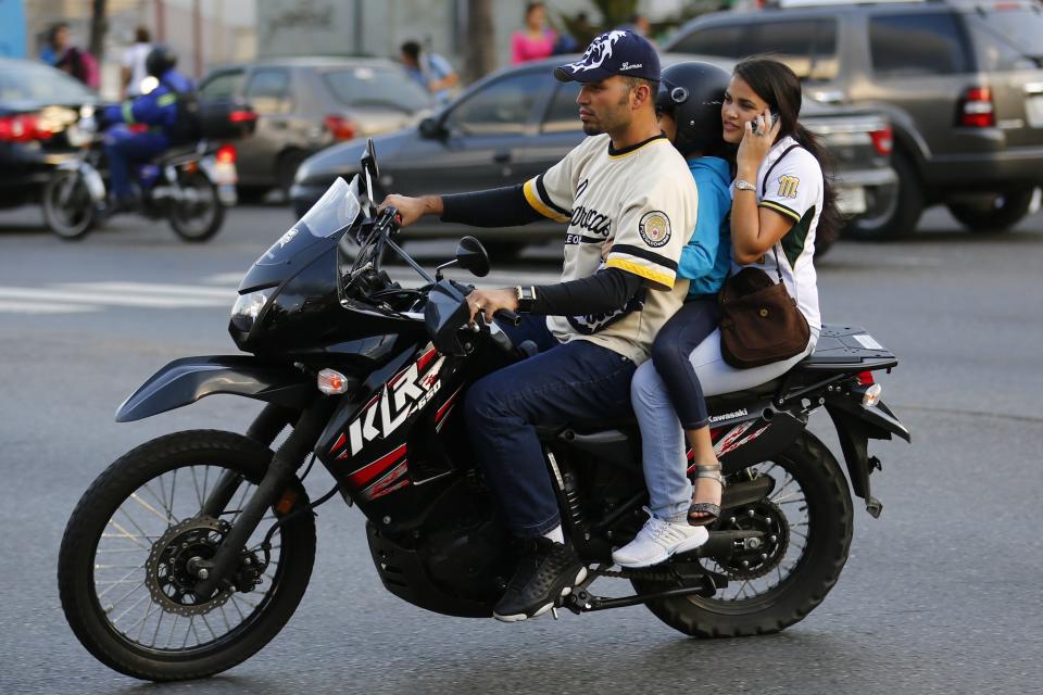 A family rides on a motorcycle among the traffic in Caracas