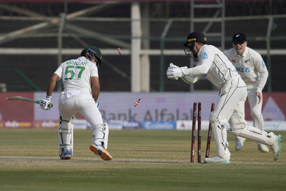 Pakistan's Abdullah Shafique, left, looks back after stump out by New Zealand's Tom Blundell, center, during the first day of first test cricket match between Pakistan and New Zealand, in Karachi, Pakistan, Monday, Dec. 26, 2022. (AP Photo/Fareed Khan)