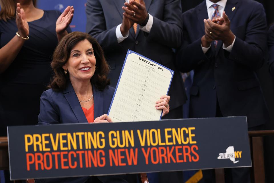 NEW YORK, NEW YORK - JUNE 06: Gov. Kathy Hochul holds up signed legislation as she is surrounded by lawmakers during a bill signing ceremony at the Northeast Bronx YMCA on June 06, 2022 in New York City. Gov. Hochul signed a series of gun reform bills, that will strengthen already strict gun laws in the state. Passed by lawmakers last week, one restriction includes banning anyone under age 21 from buying or possessing a semi-automatic rifle, among a series of other changes. The bills were passed in the wake of two recent mass shootings where an 18-year-old man fatally shot 10 people and injured 3 in Buffalo, New York and just 10 days later an 18-year old man shot and killed 19 children and 2 adults at an elementary school in Uvalde, Texas. (Photo by Michael M. Santiago/Getty Images) ORG XMIT: 775821322 ORIG FILE ID: 1401372902