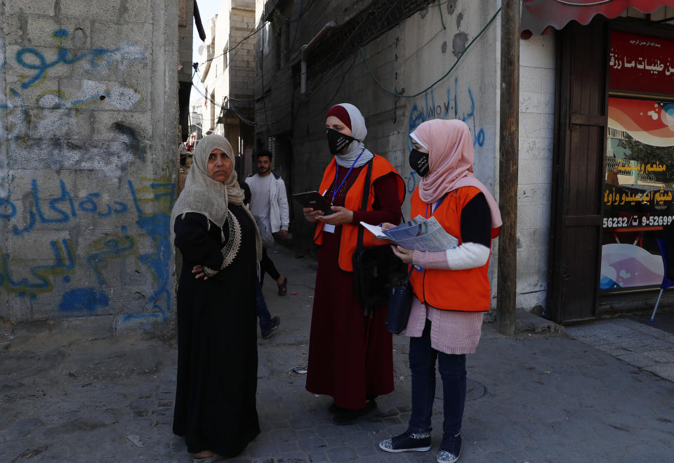 Members of the Central Elections Commission's field team checks to register a local woman to the electoral roll, at the main road of Gaza City, Feb. 10, 2021. Palestinian poll workers fanned out across the Gaza Strip on Wednesday, where they found voters eager to register ahead of elections that could serve as the first referendum on Hamas' rule since the militant group seized power more than a decade ago. (AP Photo/Adel Hana)