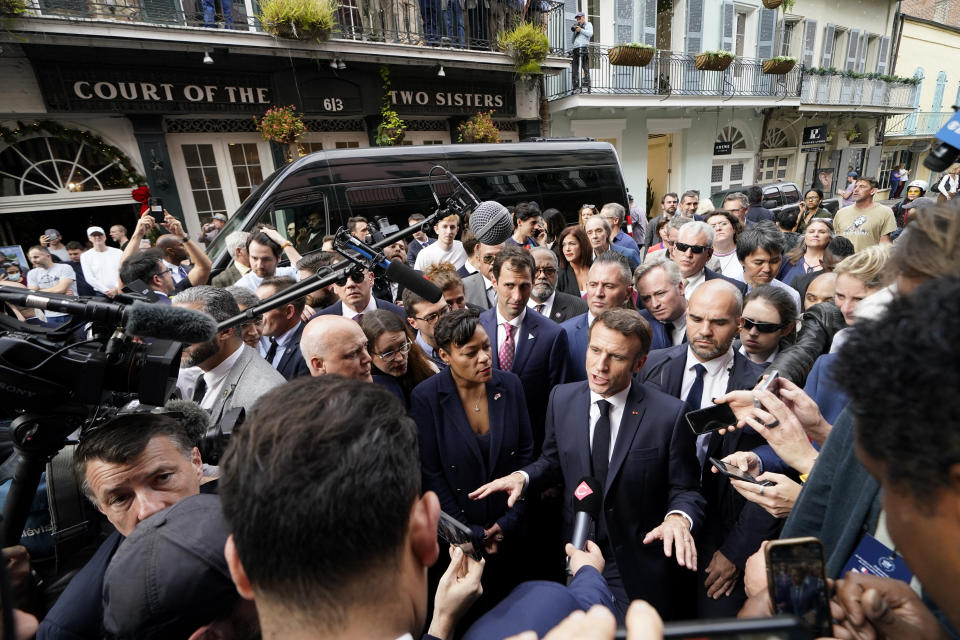 French President Emmanuel Macron speaks to reporters as he walks down Royal Street in the French Quarter of New Orleans, Friday, Dec. 2, 2022. Left is New Orleans Mayor Latoya Cantrell. (AP Photo/Gerald Herbert)