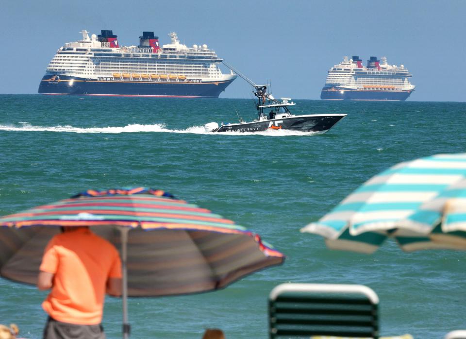 A sports fisherman passes the Disney Cruise Line ships "Fantasy," left, and "Dream" on the horizon as they sit stationary off of Cocoa Beach, Florida.