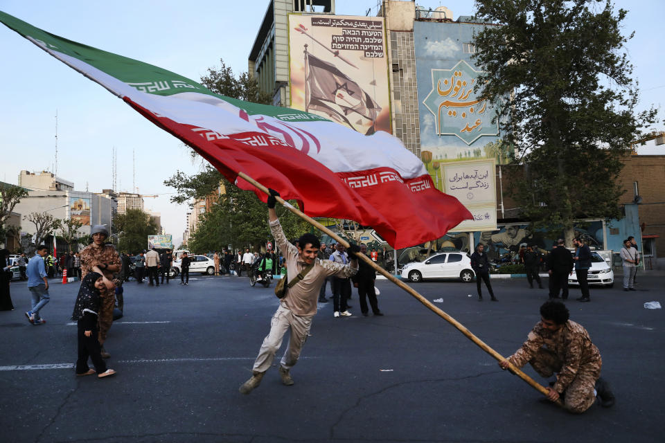 Demonstrators wave a huge Iranian flag backdropped by a building emblazoned with anti-Israeli messages, in Tehran, Iran, April 15, 2024, a day after Iran launched hundreds of drones, ballistic missiles and cruise missiles in a revenge mission against Israel. The messages on the building read in Hebrew: "Your next mistake will be the end of your fake country.", and in Farsi: "The next slap will be harder.". (AP Photo/Vahid Salemi)