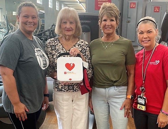 Marlana Solgot, Evelyn Chappelear and and Des Belcher presents an AED machine to Polly Pletcher, second from right, owner of  New Dimensions Tan and Gym in New Lexington.