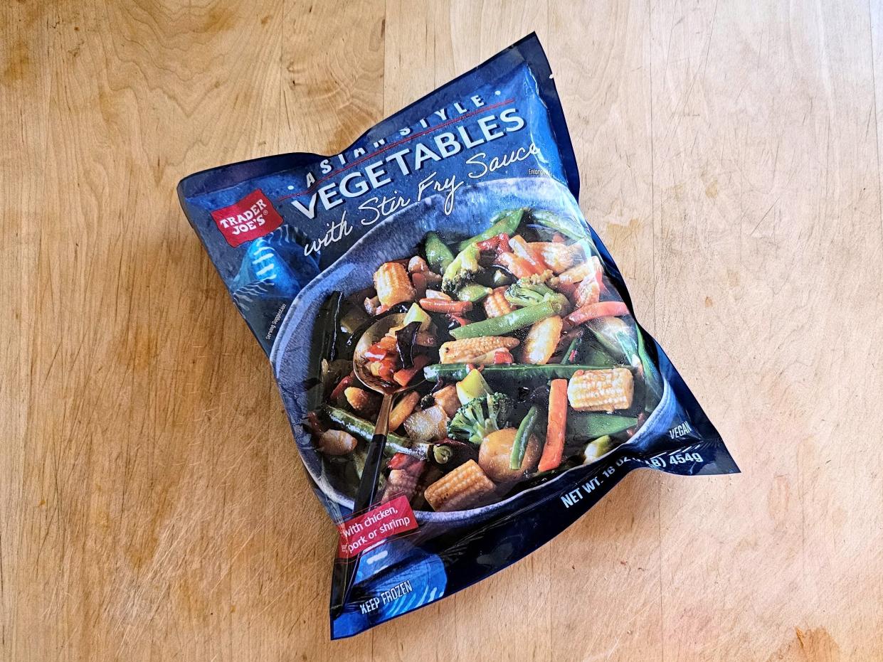 A bag of Trader Joe's Asian-style vegetables with stir-fry sauce on a wooden background.