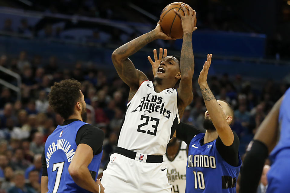 Los Angeles Clippers guard Lou Williams (23) shoots between Orlando Magic guards Evan Fournier (10) and Michael Carter-Williams (7) during the second quarter of an NBA basketball game in Orlando, Fla., Sunday, Jan. 26, 2020. (AP Photo/Reinhold Matay)