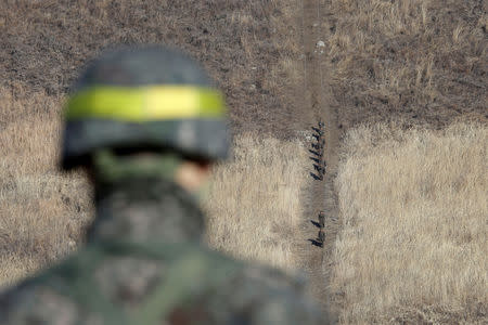 North Korean army soldiers head to inspect the dismantled South Korean guard post inside the Demilitarized Zone (DMZ) as a South Korean army soldier stands guard in the central section of the inter-Korean border in Cheorwon, December 12, 2018. Ahn Young-joon/Pool via REUTERS