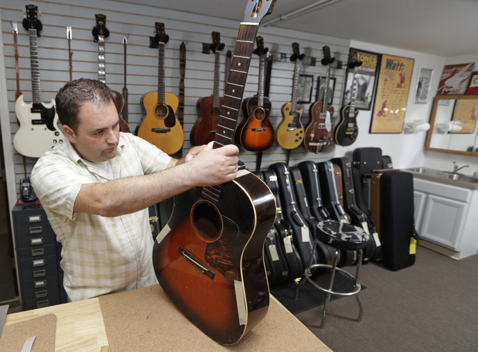 Jacob Tuel, owner of Burning River Guitars, repairs the neck of a guitar, Monday, June 10, 2019, in Akron, Ohio. Tuel named his guitar shop after the 1969 blaze on the Cuyahoga River, in Cleveland. (AP Photo/Tony Dejak)